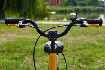 Fototapeta na wymiar Kids yellow bicycle in park, close up parts, rudder with brakes and bell