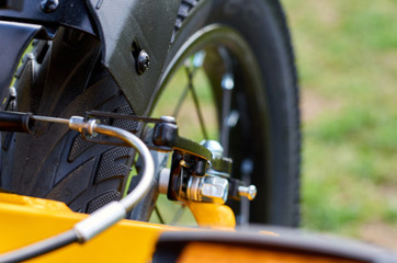 Kids yellow bicycle in park, close up parts, rear tire with brakes