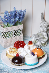 A variety of cakes on a white plate stand on a decorated table.