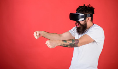 Virtual racing concept. Man with beard in VR glasses driving car, red background. Guy play racing game in VR. Hipster on excited face driving car on high speed in virtual reality