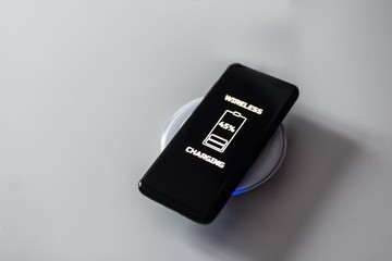 Black touchscreen smartphone wireless charging on induction charger