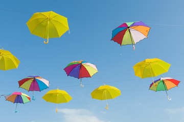 Fototapeta na wymiar Symbol of summer, many open multi-colored umbrellas on sky background.