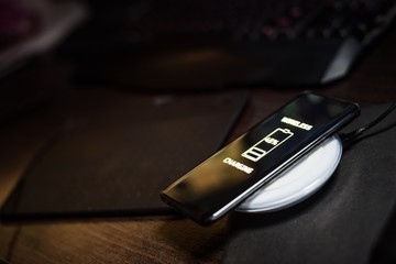 Touchscreen smartphone wireless charging on induction charger. © Daniel Jędzura