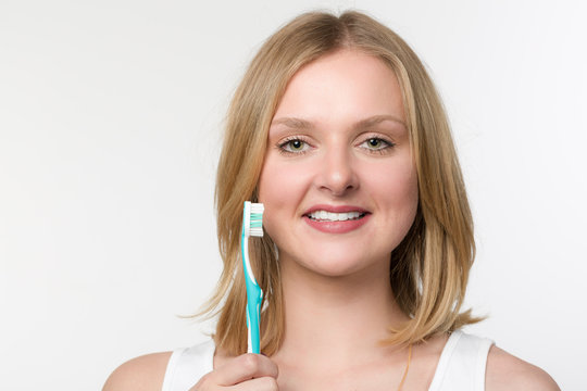 Junge Frau hält eine Zahnbürste und lächelt