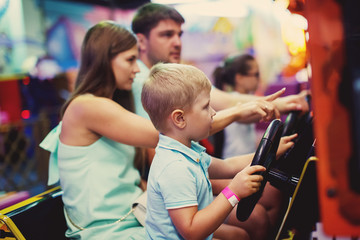 Cute girl plays a rifle shoots arcade in game machine at an amusement park.