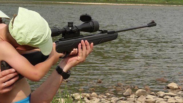 child learns to shoot an air rifle gun with optical sight. slow motion