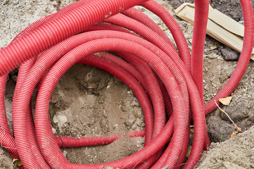 Close up of corrugated red drain pipe lays on the ground.