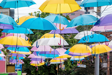 Multicolored umbrellas on the street of a modern city on a holiday day_