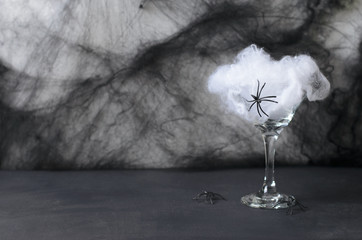 Halloween Cocktail Food Concept, Glass with Cobweb with Black Bat and Spider on Dark Background