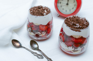 Strawberry dessert with chocolate chips, banana and sour cream in the glass.