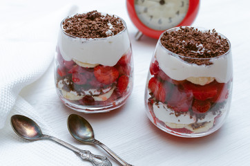 Strawberry dessert with chocolate chips, banana and sour cream in the glass.
