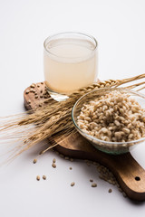 Barley water in glass with raw and cooked pearl barley wheat/seeds. selective focus