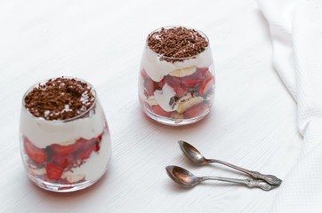 Strawberry dessert with chocolate chips, banana and sour cream in the glass.