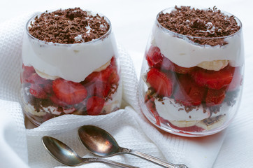 Strawberry dessert with chocolate chips, banana and sour cream in the glass.