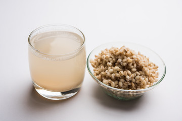 Barley water in glass with raw and cooked pearl barley wheat/seeds. selective focus