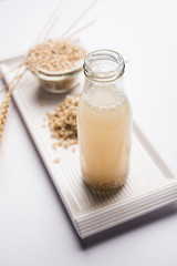 Barley water in glass bottle with raw and cooked pearl barley wheat/seeds. selective focus