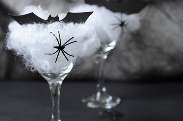 Naklejka na ściany i meble Halloween Cocktail Food Concept, Glass with Cobweb with Black Bat and Spider on Dark Background