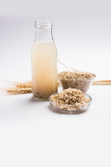 Barley water in glass bottle with raw and cooked pearl barley wheat/seeds. selective focus