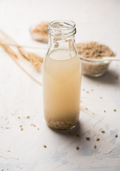 Barley water in glass bottle with raw and cooked pearl barley wheat/seeds. selective focus