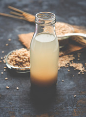 Barley water in glass bottle with raw and cooked pearl barley wheat/seeds. selective focus