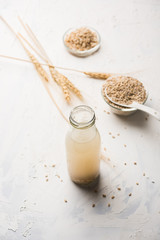 Barley water in glass bottle with raw and cooked pearl barley wheat/seeds. selective focus