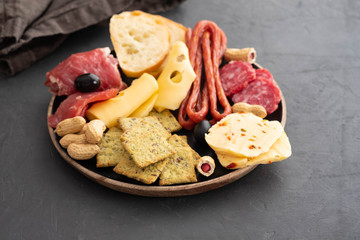 Meat and cheese plate.Traditional italian antipasto, cutting board with salami, cold smoked meat, prosciutto, ham, cheeses, olives, capers on black background. Cheese and meat appetizer. Top view.