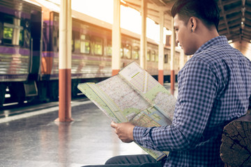 Obraz premium Traveler man sitting at train station and looking on map for travel planning.