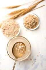 Barley water in glass bowl with spoon and raw and cooked pearl barley wheat/seeds. selective focus