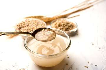 Barley water in glass bowl with spoon and raw and cooked pearl barley wheat/seeds. selective focus