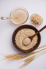 Barley water in glass bowl with spoon and raw and cooked pearl barley wheat/seeds. selective focus