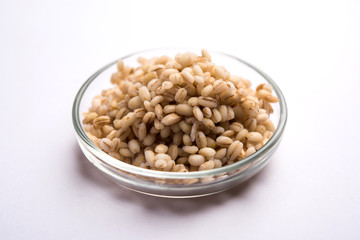 Raw and cooked Barley pearl seeds in a bowl or over white plate. selective focus