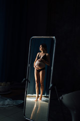 Reflection of a pregnant girl in a mirror