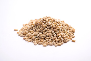 Raw and cooked Barley pearl seeds in a bowl or over white plate. selective focus