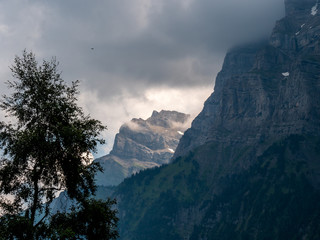 steep mountain scenery in the swiss alps covered in clouds
