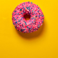 Yellow background with a pink donut sprinkled in the middle