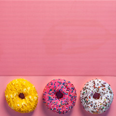 Colorful donuts with sprinkles on millennial pink copy space