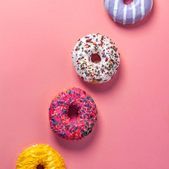 Colorful donuts in a row on a smooth pink background