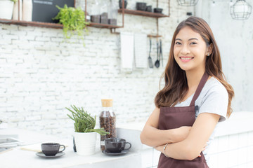 Asian Women Barista smiling and looking to camera in coffee shop counter. Barista female working at cafe. Working woman small business owner or sme concept.