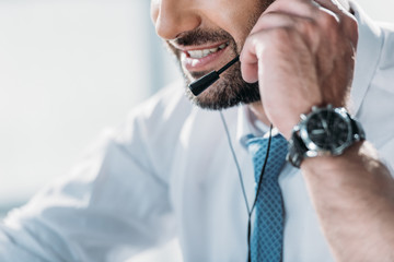cropped shot of support hotline worker in shirt with tie talking by headphones with microphone