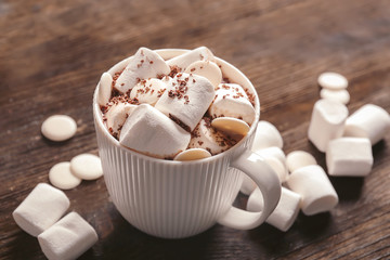 Cup of delicious hot cocoa with marshmallows on wooden background