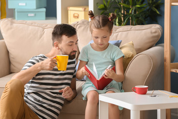 Father and his daughter reading book together at home