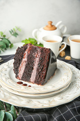 Plate with piece of delicious chocolate cake on table