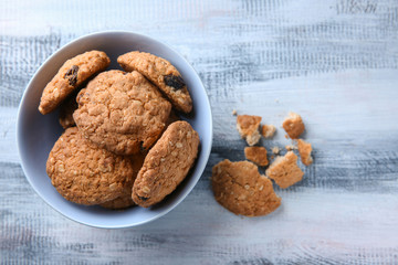 Bowl with delicious oatmeal cookies on wooden background