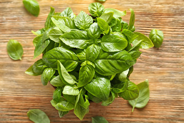 Bowl with fresh green basil on wooden background