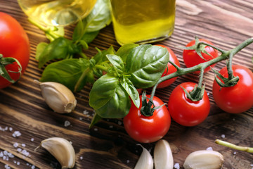 Fresh green basil with tomatoes and spices on wooden background