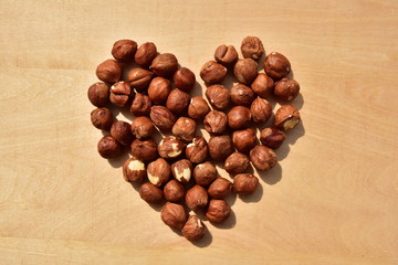 Whole nuts hazelnut layed out in the shape of heart on the woode bacground