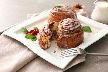 Plate with tasty cinnamon buns on table
