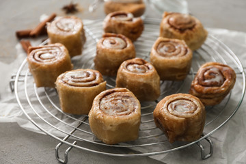 Cooling rack with tasty cinnamon buns on table