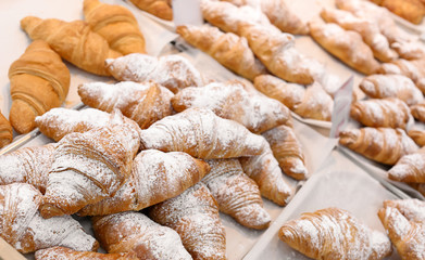 Fresh tasty croissants on display in bakery