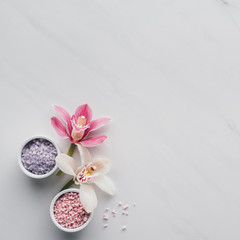 top view of beautiful orchid flowers and sea salt in bowls on white background